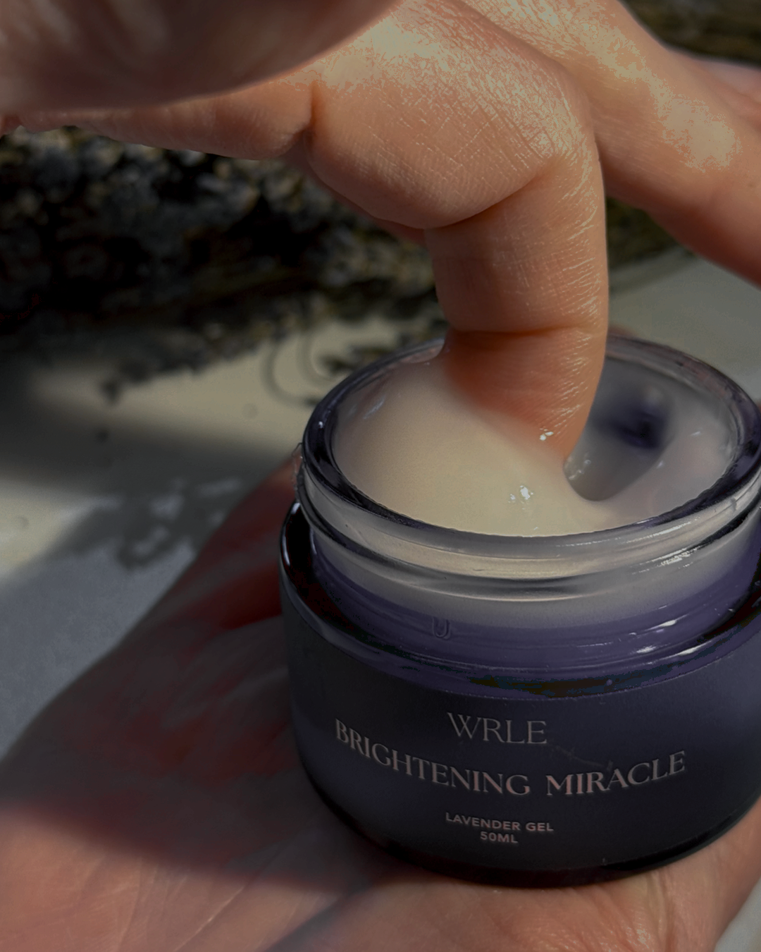 Hand holding a jar of 'Brightening Miracle' cream with a blurred background